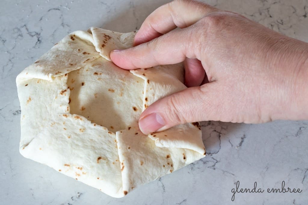 Fold the sides of the big tortilla to the center and over the quartered piece.