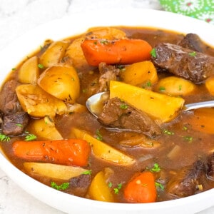 Slow Cooker Beef Stew served in a white bowl next to a green print napkin